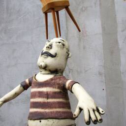 Ceramic Juggler Balancing A Hand Carved Chair - thumbnail 3