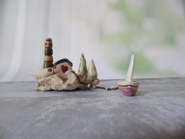 Ceramic Miniature Of A Little Village, Including Lighthouse, Green Roof House, Trees, Dove & Sail Boat Attached To Beach Stone - image 1