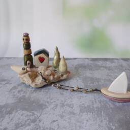 Ceramic Miniature Of A Little Village, Including Lighthouse, Green Roof House, Trees, Dove & Sail Boat Attached To Beach Stone - thumbnail 3