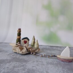 Ceramic Miniature Of A Little Village, Including Lighthouse, Green Roof House, Trees, Dove & Sail Boat Attached To Beach Stone - thumbnail 2