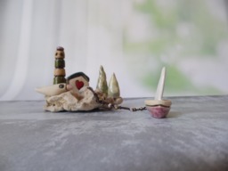 Ceramic Miniature Of A Little Village, Including Lighthouse, Green Roof House, Trees, Dove & Sail Boat Attached To Beach Stone - thumbnail 1