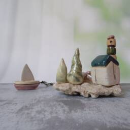 Ceramic Miniature Of A Little Village, Including Lighthouse, Green Roof House, Trees, Dove & Sail Boat Attached To Beach Stone - thumbnail 4
